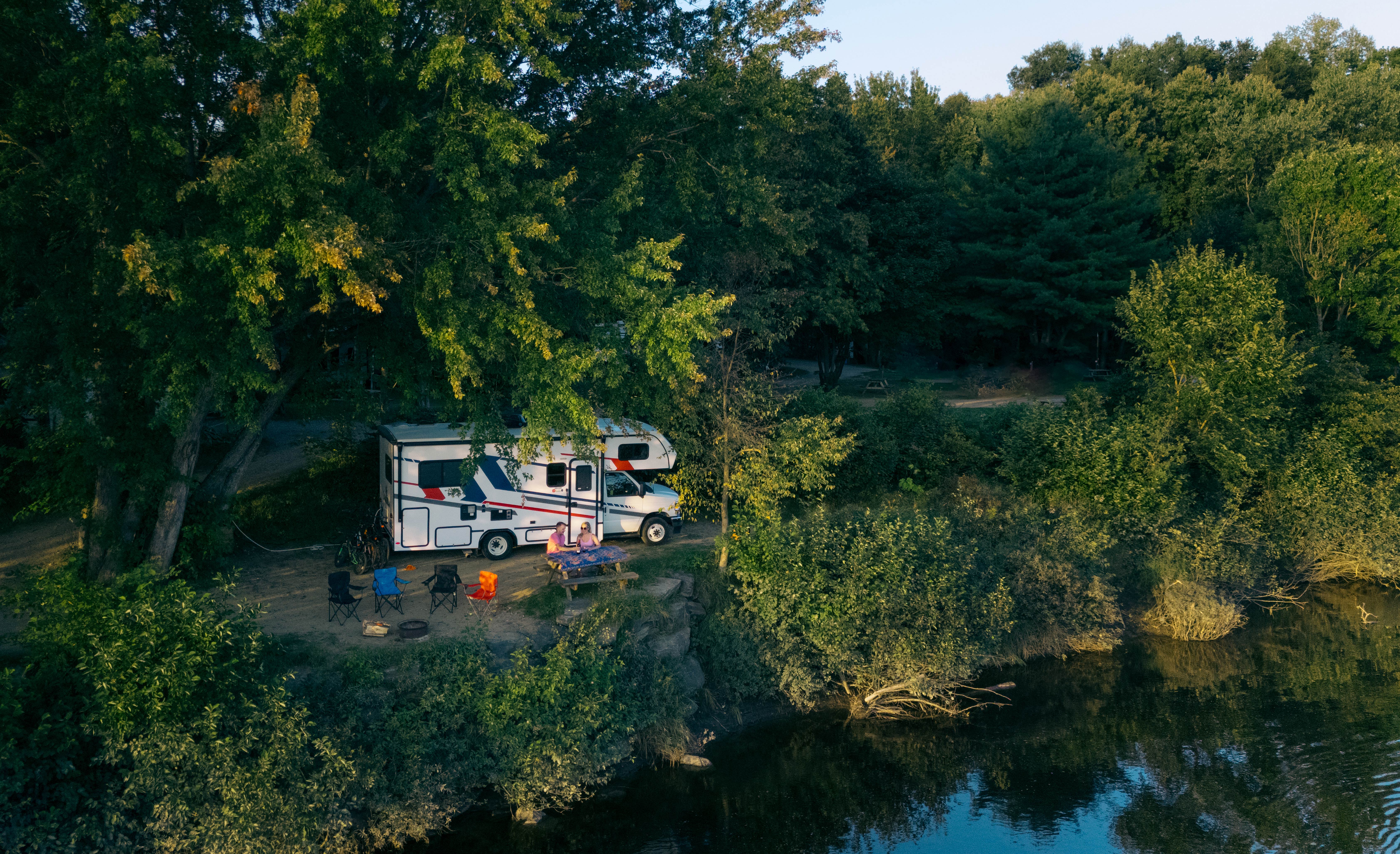 Compact Motorhome MHC Canada couple at picnic table under trees4