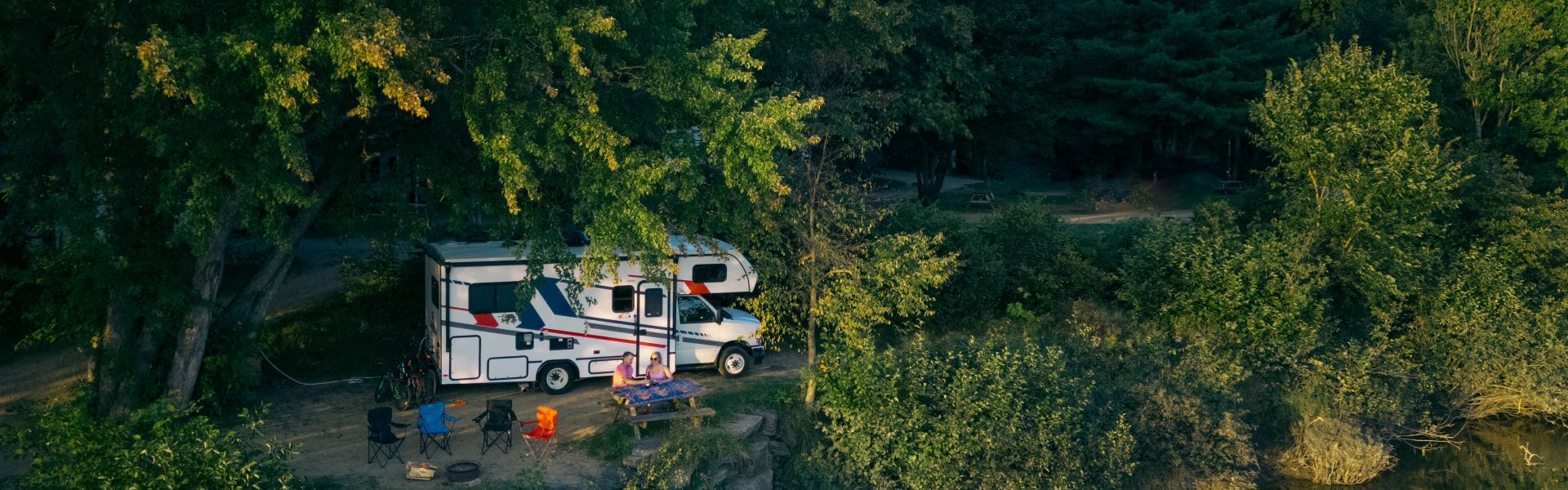 Compact Motorhome MHC Canada couple at picnic table under trees5